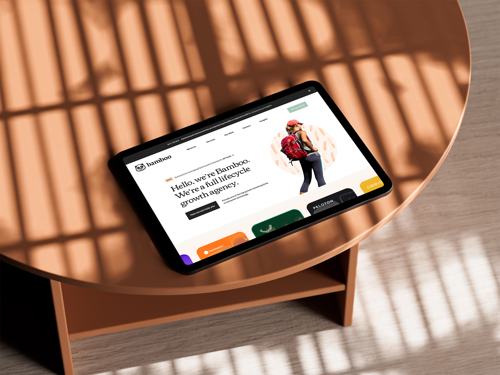 Tablet on a pink table showing the Bamboo homepage for a full-lifecycle growth agency.