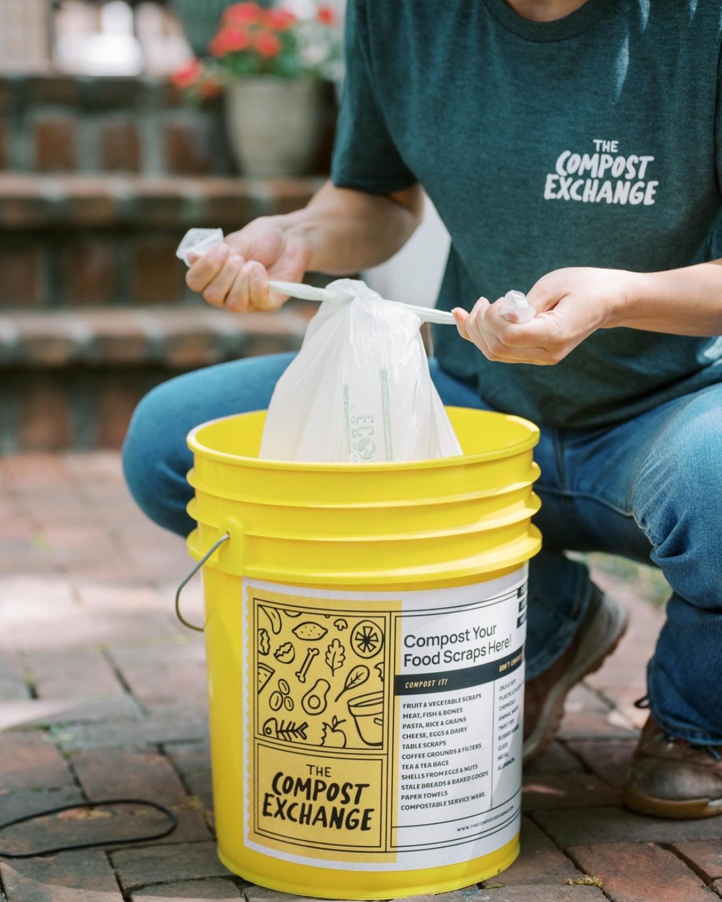 Person placing food scraps into a yellow Compost Exchange bin.