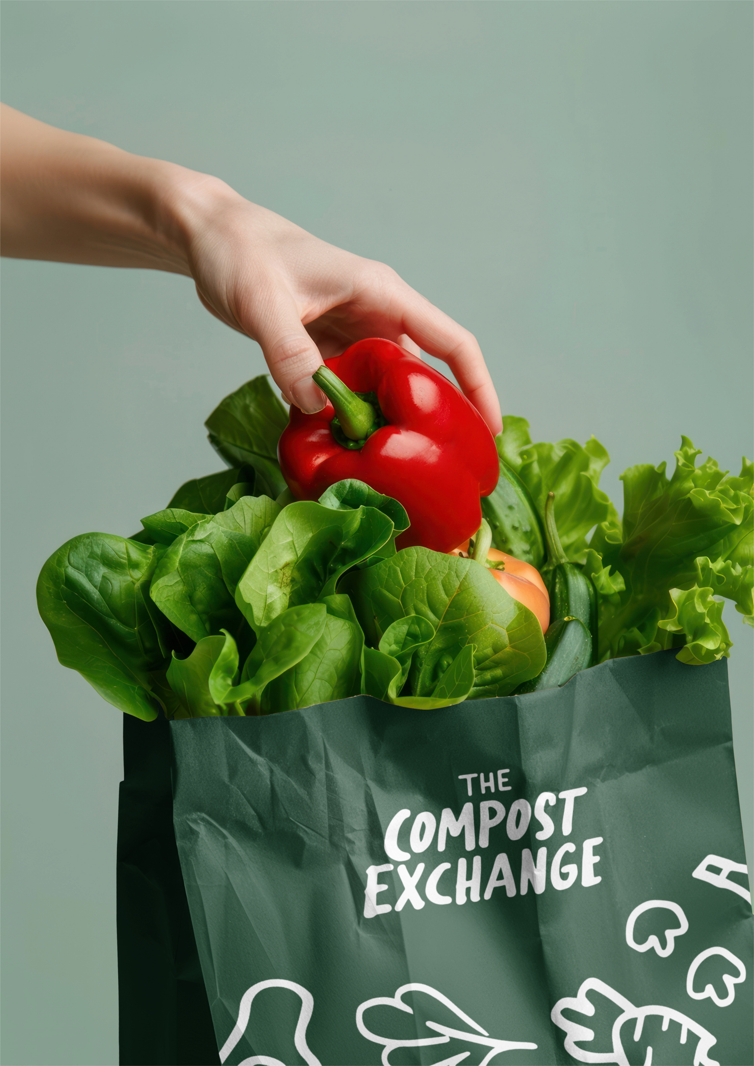 Hand placing a red pepper into a Compost Exchange produce bag.
