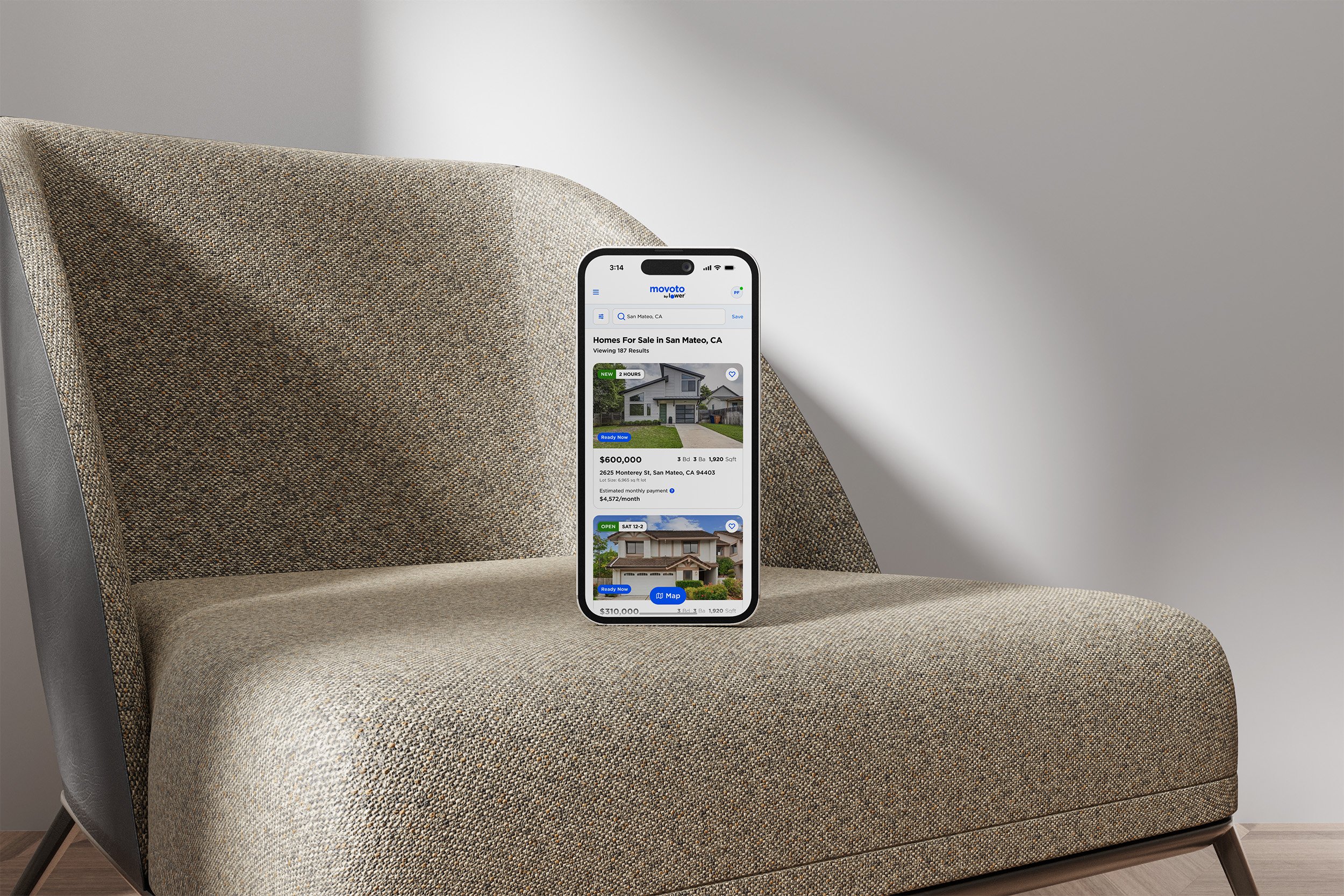Smartphone displaying real estate listings on a beige armchair.