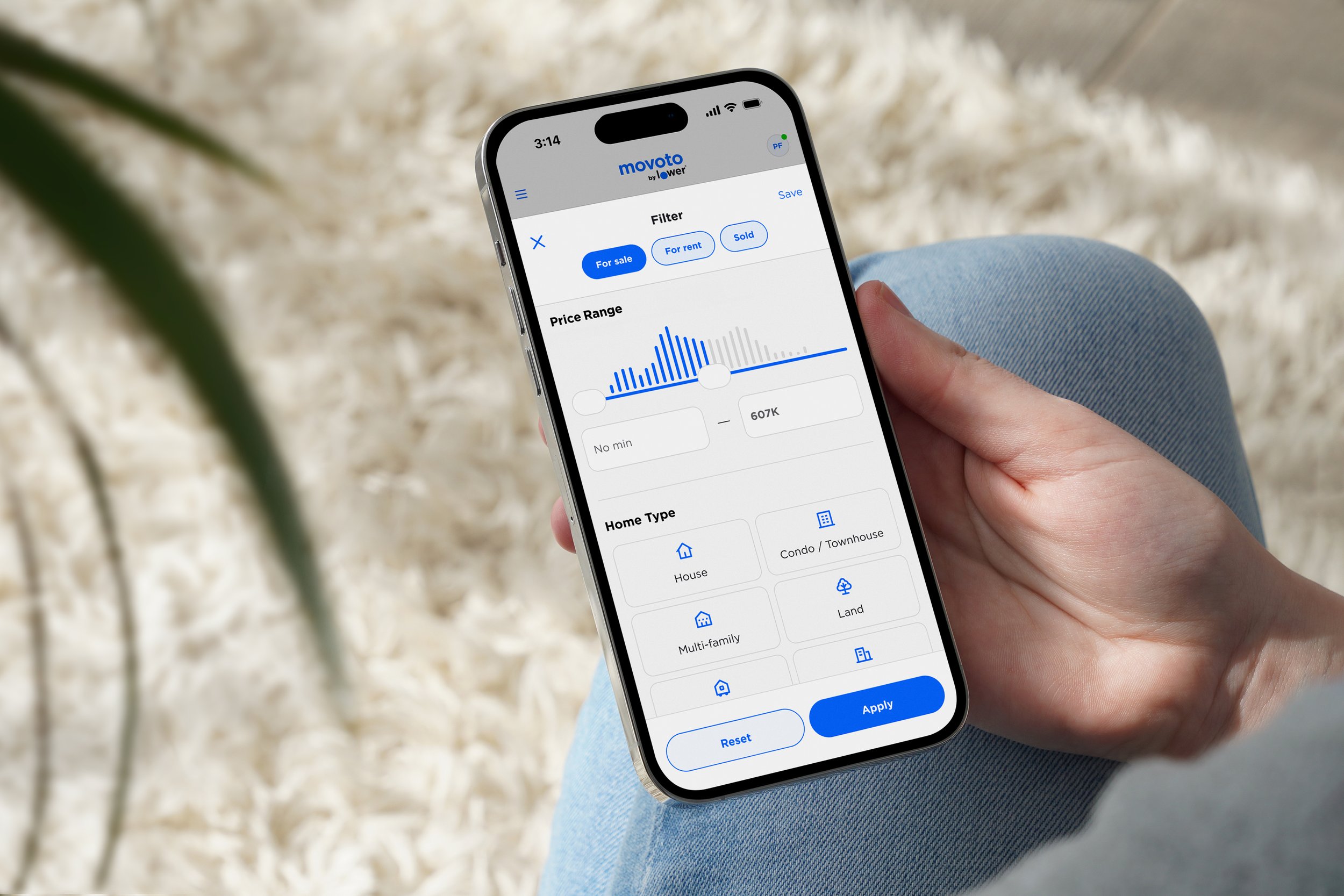 Person holding a smartphone showing real estate filters for price, home type, and sale status.