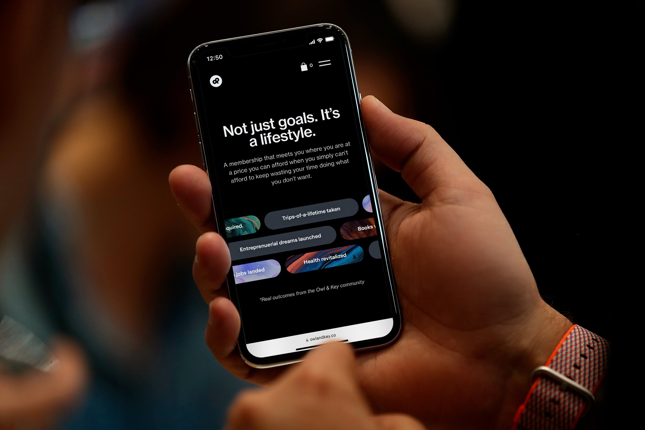 Person holding a phone showing the Owl & Key membership site.