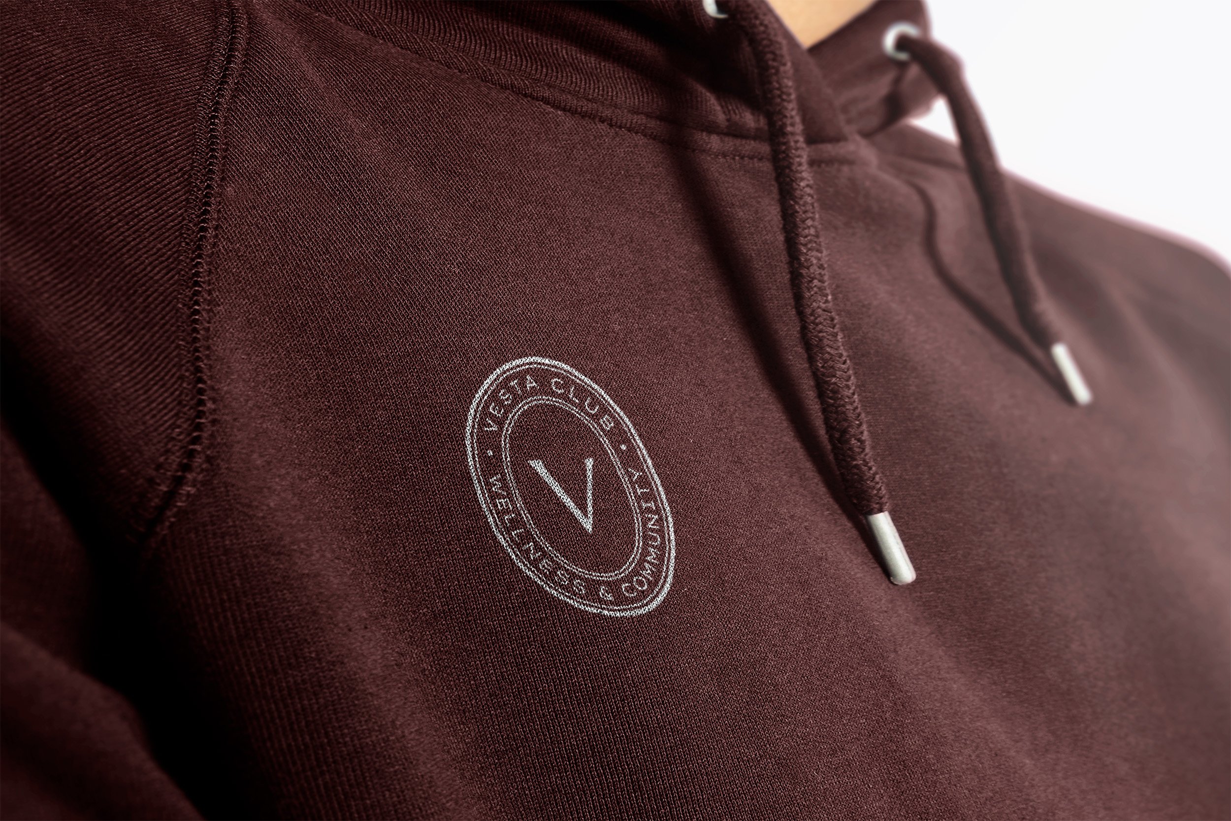 Maroon hoodie with a circular Vesta club mark.
