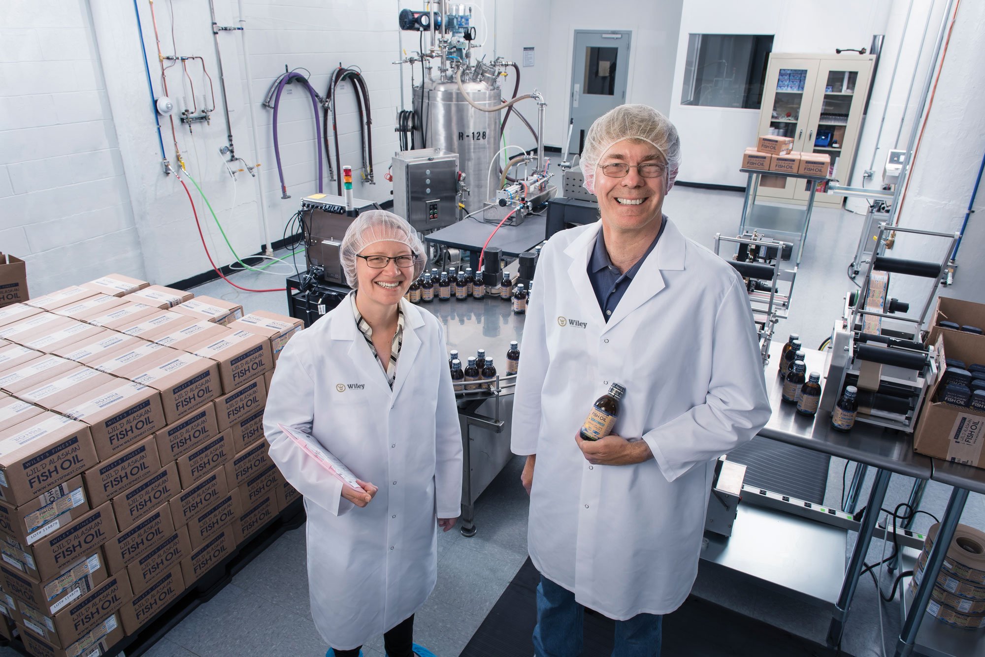 Two scientists in a lab with fish-oil products and Wiley packaging.