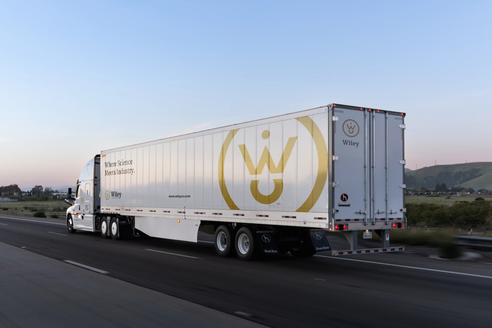 White Wiley semi-truck on a highway at sunset.